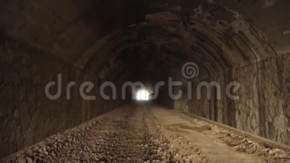 最后带着明亮的光线在旧的暗长废弃隧道内行走视频的预览图
