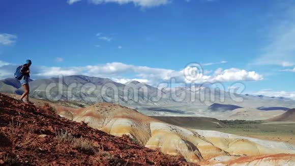 年轻的旅游妇女带着背包和帽子从红石山下来不真实的风景和视频的预览图