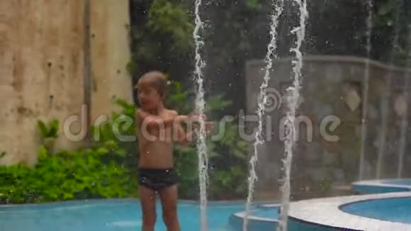 一个在热带公园玩喷泉的小男孩的慢镜头视频的预览图