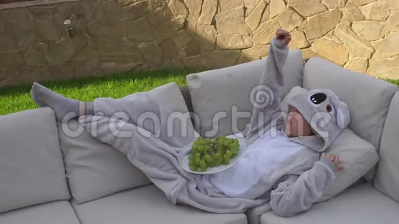 一个穿着熊猫服的女孩躺在沙发上吃葡萄视频的预览图
