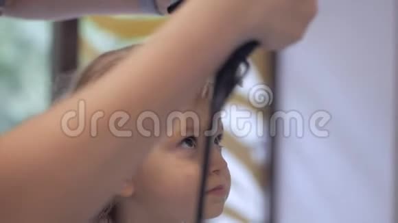 理发师给一个小女孩烘干吹风机美容院的护发视频的预览图