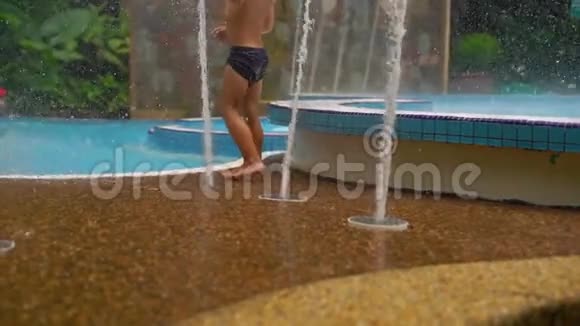 一个在热带公园玩喷泉的小男孩的慢镜头视频的预览图