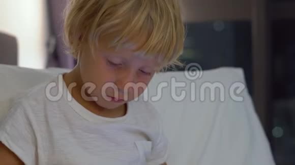 一个晚上坐在床上的小男孩近距离拍摄了一台平板电脑电脑上有摩天大楼的轮廓视频的预览图