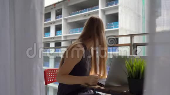 年轻女子坐在阳台上手里拿着笔记本在附近的一个建筑工地上大声喧哗视频的预览图