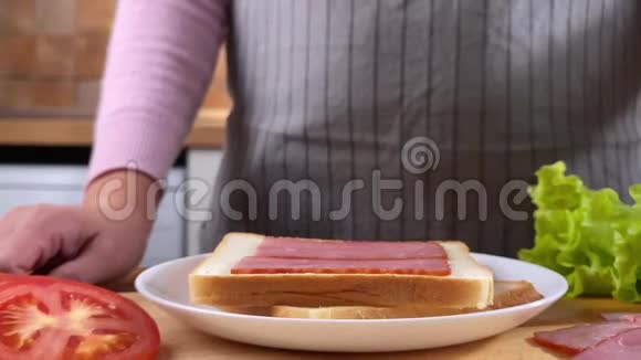 女人在厨房里做三明治配沙拉培根和番茄视频的预览图