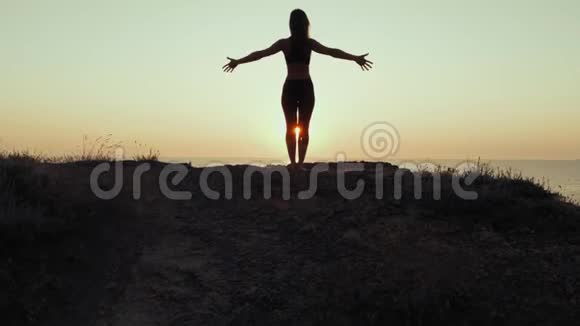 日落时分女人在山上练习瑜伽的剪影冥想自然背景下的灵活性锻炼视频的预览图