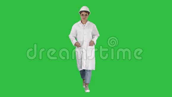 穿着白色实验室外套和戴着安全帽的女人在绿色屏幕上行走Chroma键视频的预览图