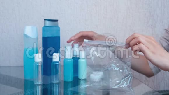 女人手把一套带瓶子和罐子的化妆品放在拉链塑料袋里特写罐子视频的预览图