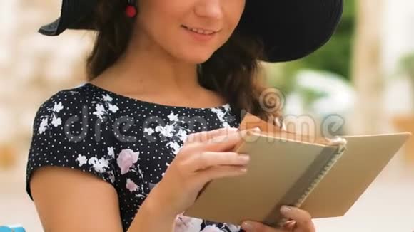 戴帽子的浪漫女士在街头咖啡馆读日记享受休息和特写视频的预览图