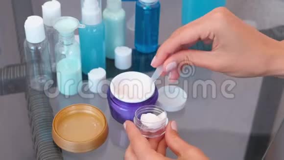 女人手把一个大罐子里的奶油放进一个小罐子里里面有一个铲子道套的化妆品特写罐子视频的预览图