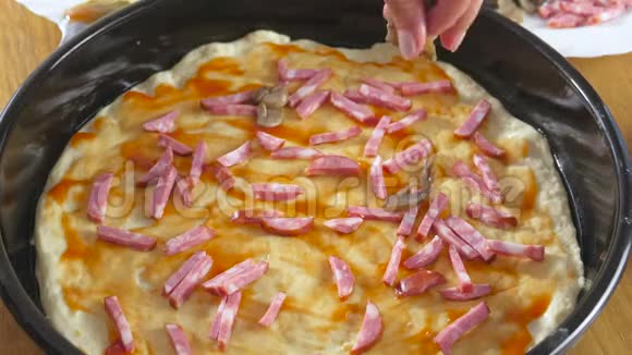 做披萨女人手做自制披萨把配料香肠和蘑菇放在面团上视频的预览图