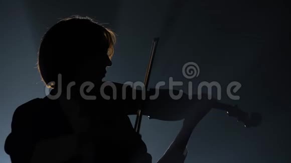 小提琴手拿着灯笼在黑暗的工作室里表演黑色背景剪影视频的预览图