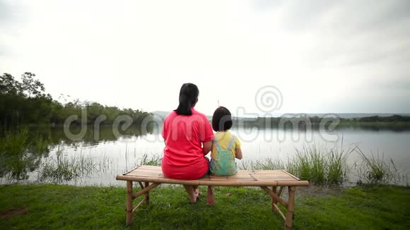 母亲和女儿在湖边钓鱼幼儿与自然联系的概念视频的预览图