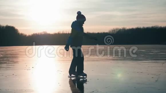 可爱的小女孩在日落时要去户外滑冰冬天一个在冰冻湖上滑冰的女生视频的预览图