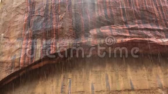 锡安国家公园的一座沙岩拱门有黑色红色铜色和黄色的条纹水在那里滴落氧化视频的预览图