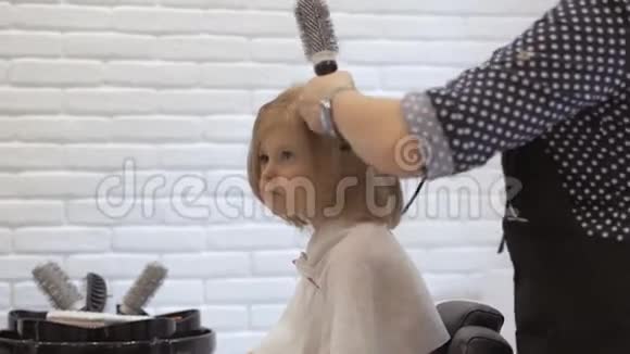 理发师给一个小女孩烘干吹风机美容院的护发视频的预览图