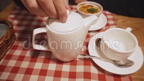 人通过提起水壶的盖子来检查茶叶在眼睛上的酿造准备情况视频的预览图