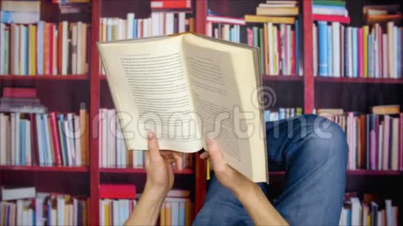 手拿书的人躺在书架上的大学图书馆里视频的预览图