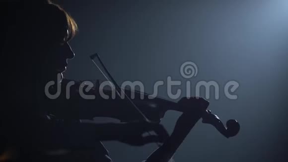 小提琴手拿着灯笼在黑暗的工作室里表演黑色背景剪影视频的预览图