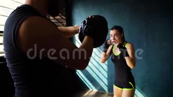 跟踪适合白人女性拳击手训练与拳击教练在健身房视频的预览图