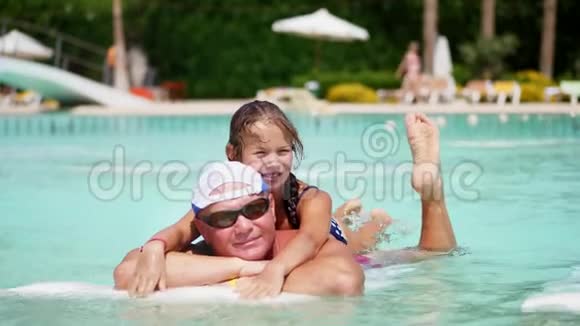 戴着太阳眼镜的男人爸爸和女儿小女孩在游泳池里玩一起玩快乐家庭放松视频的预览图