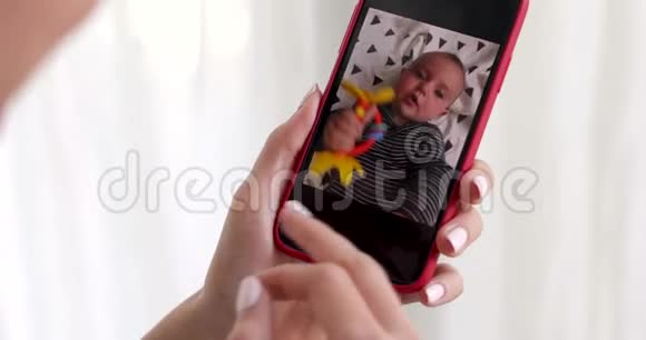 女人手拿智能手机显示孩子的照片视频的预览图