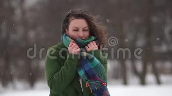 公园里的小卷曲女孩下雪了那个女人穿着一件没有帽子和手套的外套冻住了裹在围巾里视频的预览图