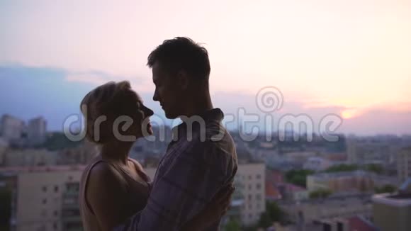 一对美丽的情侣沐浴在怀抱中从高楼的屋顶欣赏日落视频的预览图