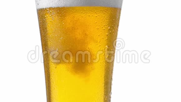 特写慢动作冷啤酒从白色背景的瓶子里倒入玻璃杯中泡沫中有气泡视频的预览图