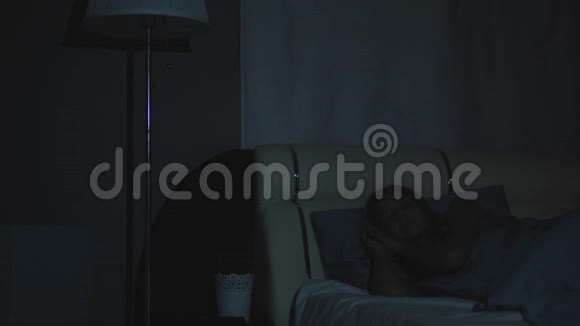 女人在夜晚醒来打开灯打开电话视频的预览图