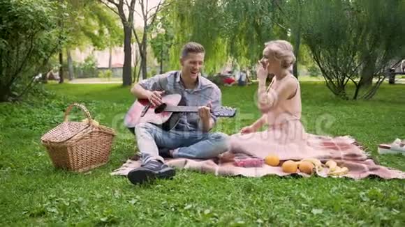 有浪漫约会唱歌弹吉他的情侣坐在公园里视频的预览图