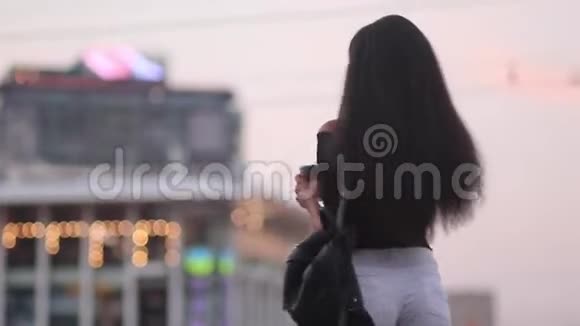 年轻女子端着一杯咖啡站在城市大街上微笑视频的预览图