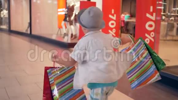 时尚购物在昂贵的精品店购买后顾客手拿包裹穿过购物中心视频的预览图