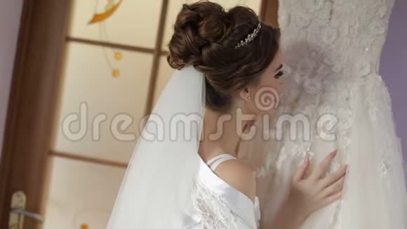 美丽可爱的新娘穿着睡衣站在婚纱附近结婚的早晨漂亮又整洁的女人视频的预览图
