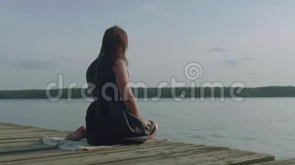穿着黑色衣服的女人坐在老码头上看着前面转过身来看着相机用手势打电话相机明星视频的预览图
