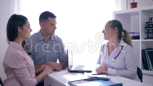 关于女性健康的谈话医生为一对幸福的夫妇在医疗办公室带来好消息视频的预览图