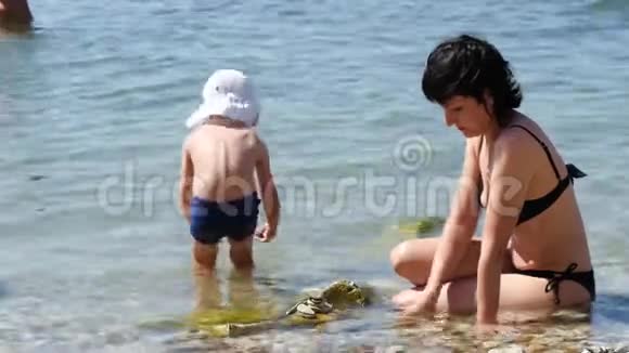 孩子和他妈妈把鹅卵石放在海滩上家庭幸福观与家庭度假视频的预览图