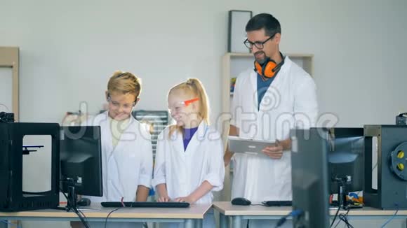 一个十几岁的男孩和一个女孩正和一个研究人员一起看着一台电脑显示器视频的预览图