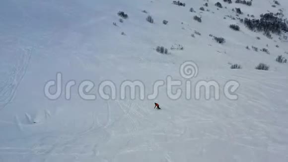 一名男子在新鲜的粉末雪上自由下山的空中镜头4k视频的预览图
