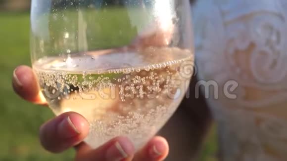把起泡的葡萄酒从瓶子里倒入透明的玻璃杯里手里拿着一杯香槟女孩手里拿着火花和泡沫视频的预览图