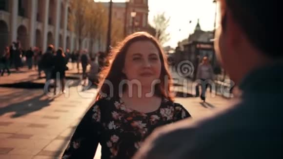 迷人的黑发女人满脸雀斑的跑过来拥抱她的男朋友在城市街道看镜头视频的预览图
