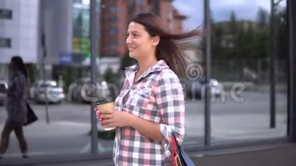 年轻女孩买东西后手里拿着袋子喝咖啡4K视频的预览图