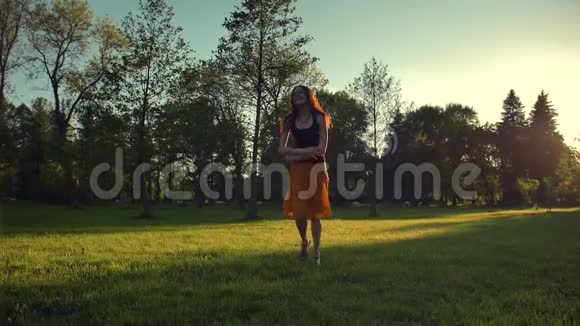 迷人的女性穿着红色长裙在公园里户外跳跃和跳舞视频的预览图