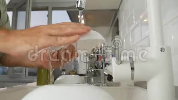 与男士在室内用清水喷射洗涤水槽中的慢动作视频的预览图
