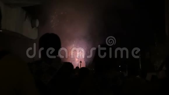在城市的一个漆黑的夜晚人们看着爆炸的烟花剪影视频的预览图