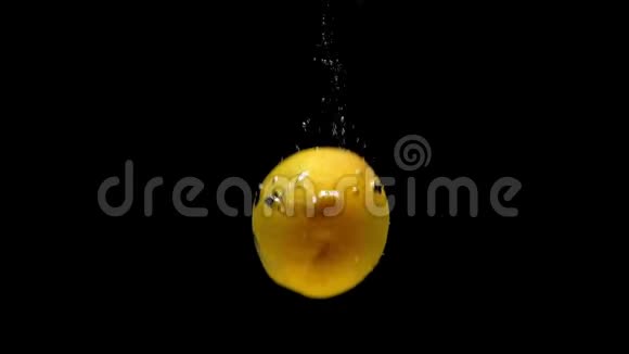 成熟的杏子在黑色的背景上落入透明的水中视频的预览图
