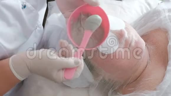 面部皮肤清洁和提升的治疗程序美容师在一个灰色的海藻酸钠面具上视频的预览图