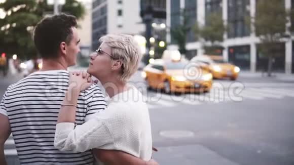 慢动作微笑的年轻白种人女孩拥抱和亲吻她的男朋友站在繁忙的纽约街头视频的预览图