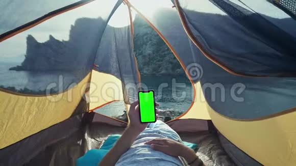 贴在帐篷上的太阳能电池板坐在手机旁边的那个人从阳光下收费一个年轻人躺在视频的预览图