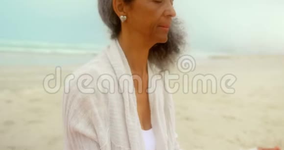 活跃的非洲裔美国老年妇女在海滩上练习瑜伽的侧视图视频的预览图